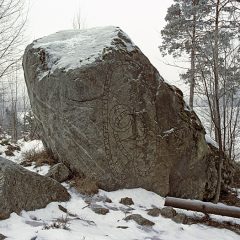 Bilden föreställer ett stort stenblock med en runristning i ett snölandskap