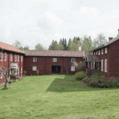 Exteriör med tre stycken ädre hus med röd träpanel står i en vinkel.