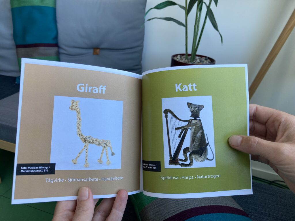 Uppslag i broschyr med bilder på museiföremål i form av en katt och giraff.