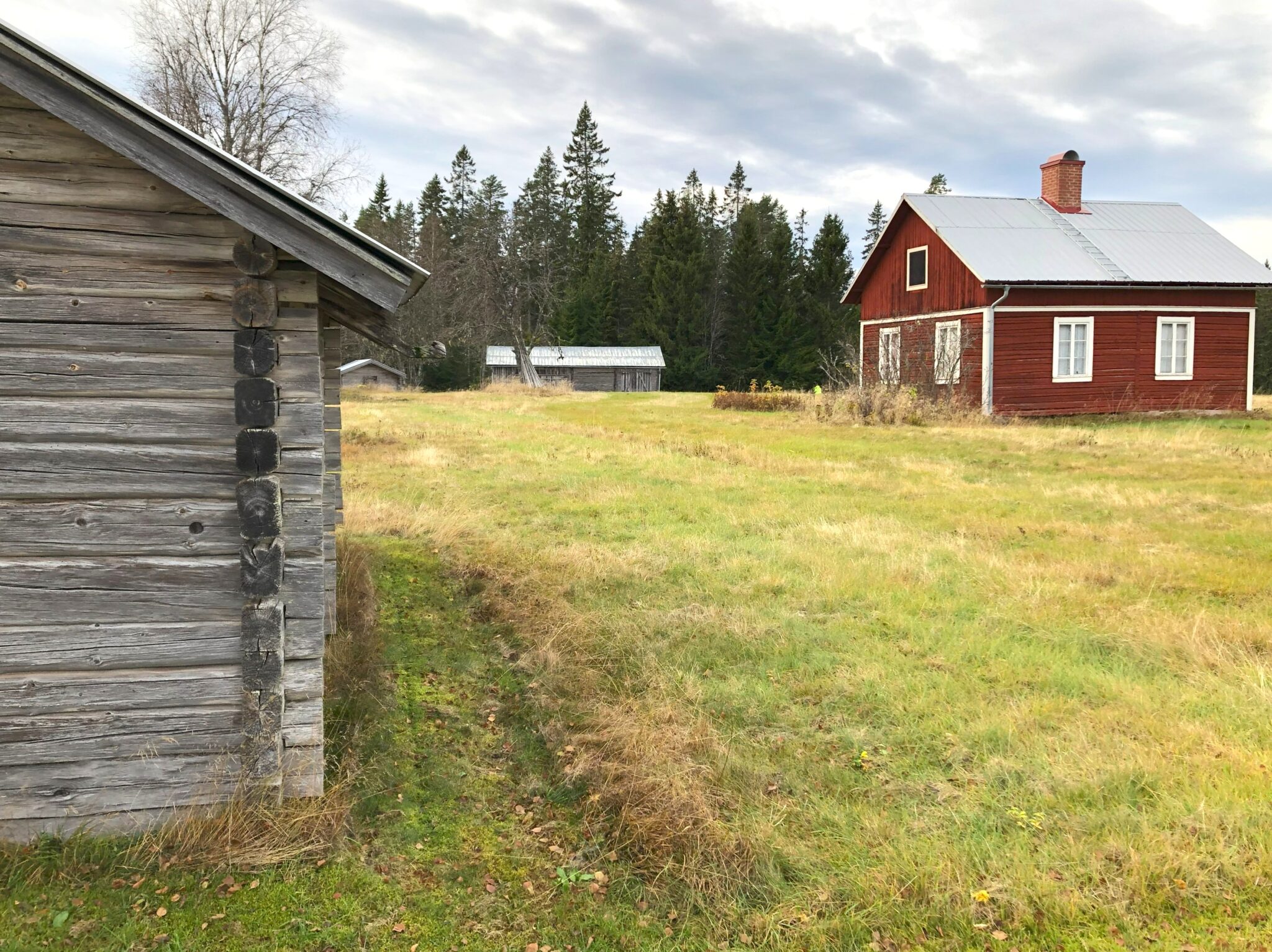 En säter i Värmland. En stuga i förgrunden till vänster. En boningsstuga syns til höger i bild. Den är röd.